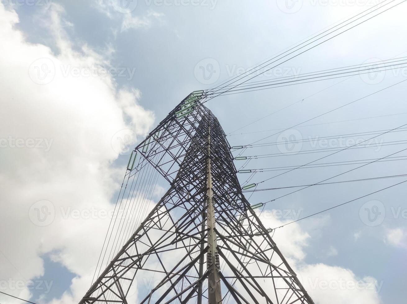 Low-angle shot electrical pylon with ultra high voltage. An electrical distribution power line with bright sunlight, few clouds, and a clear sky in the background. Electrical industry with ads space photo