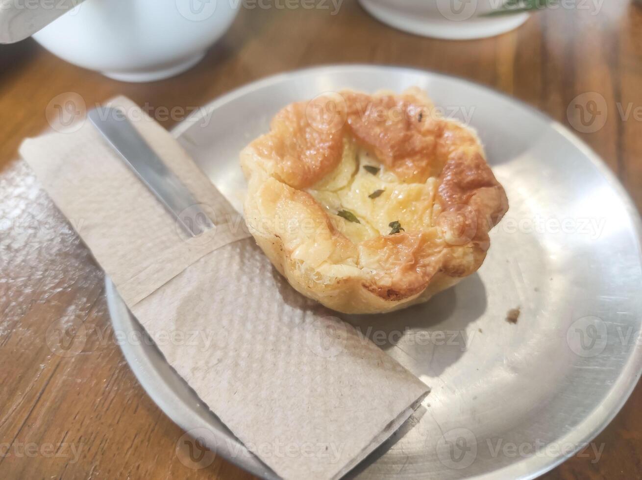 Tabletop shot baked egg tart. Egg tart dessert with a browned and crispy crust served on a plate on a wooden table. Indonesian gourmet dessert. Tasty and delicious. Text space photo