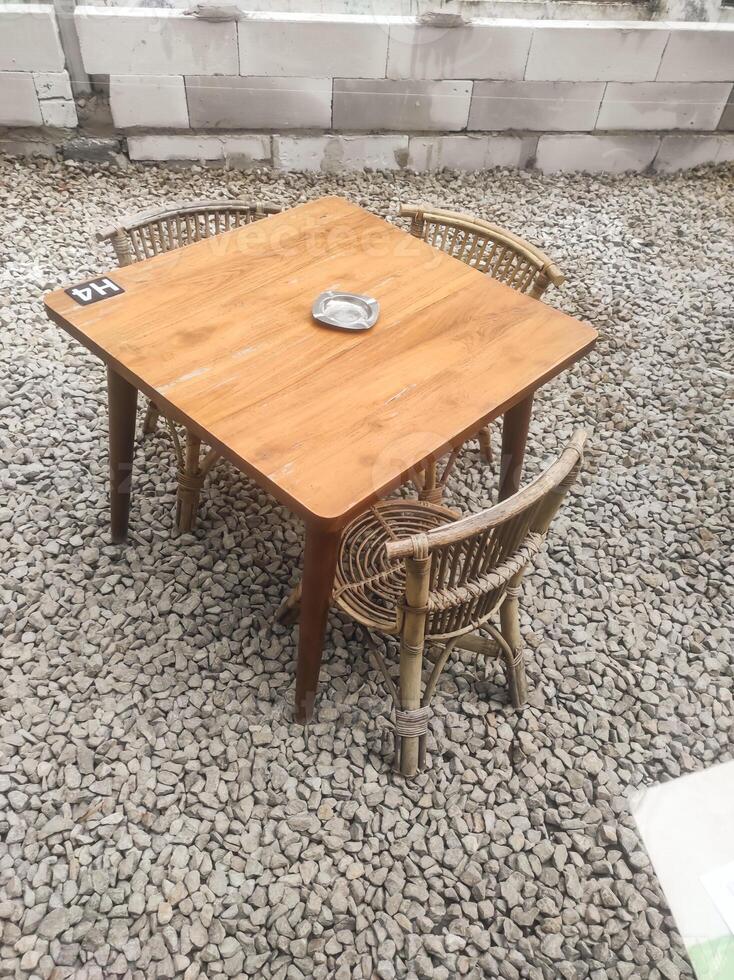 Outdoor cafes feature wooden or woven bamboo benches and tables on rocky ground. A hangout area is provided outside the cafe or restaurant. Interior design with negative space. photo