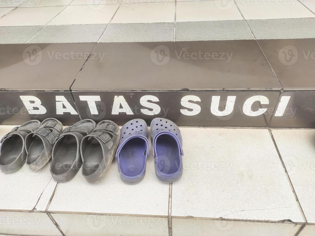 Several pairs of sandals on the floor with the inscription holy boundary. Everyone must remove their shoes upon entering the mosque area. Signs and symbols found in the mosque, Copy space photo