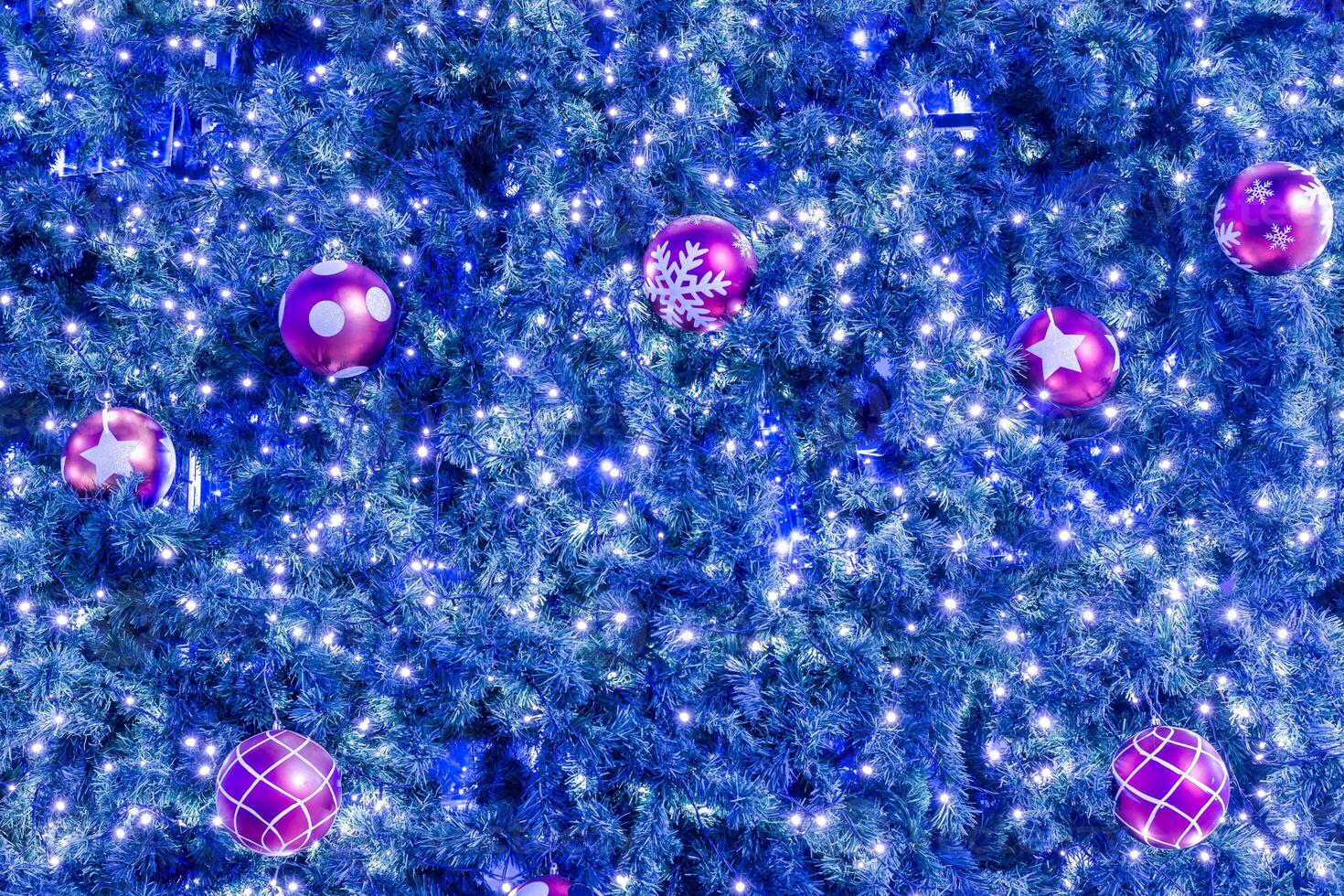 A blue christmas tree with many pink and purple balls photo