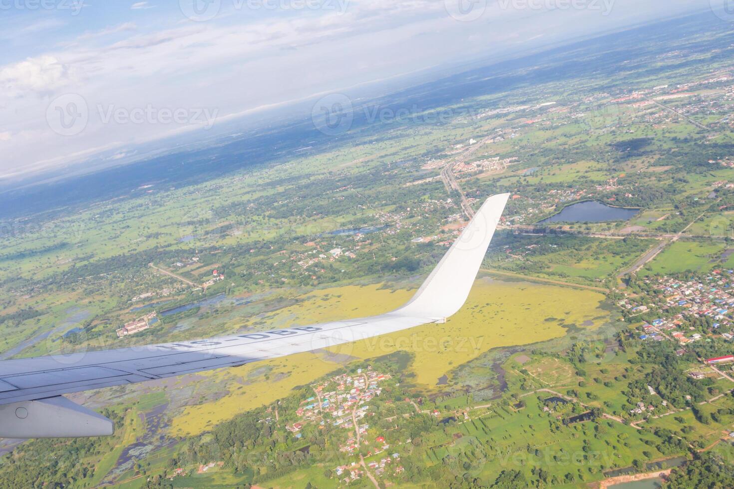A view of a plane flying over a green field photo