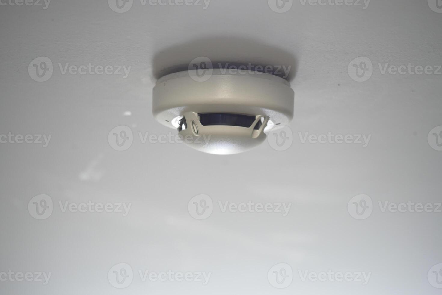 Smoke detector installed on a ceiling indoors photo