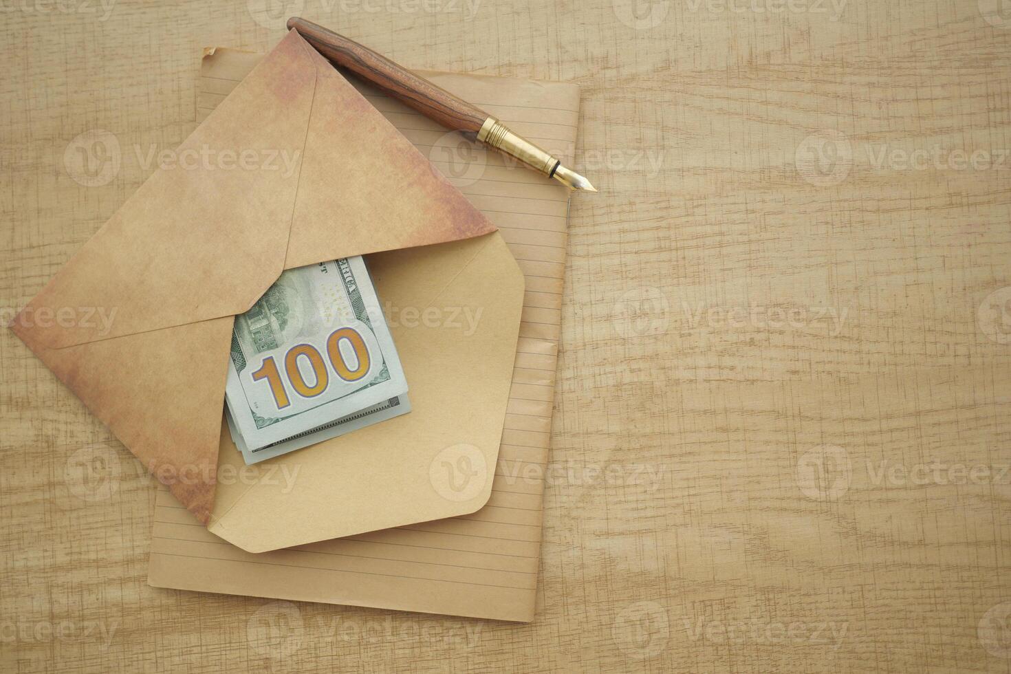 Money in an envelope with a pen on a wooden desk photo