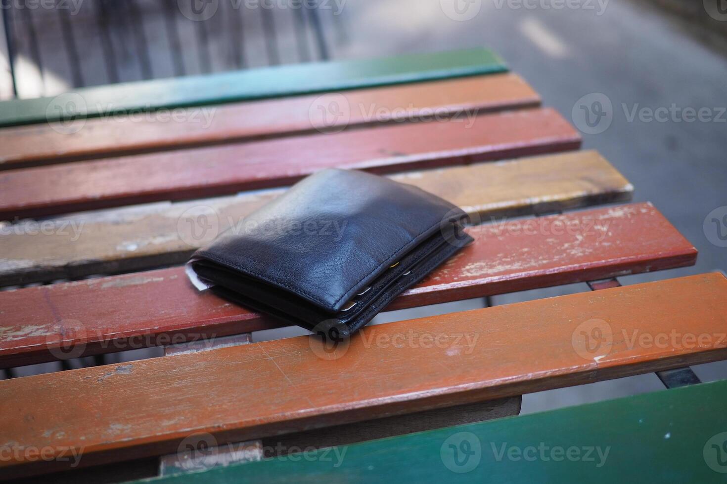 Black wallet resting on colorful wooden table outside, lost wallet concept photo