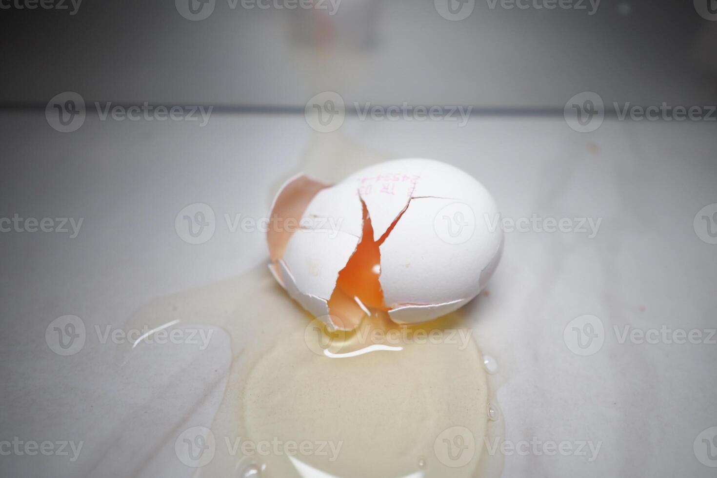 Cracked egg spills yolk on a smooth surface photo