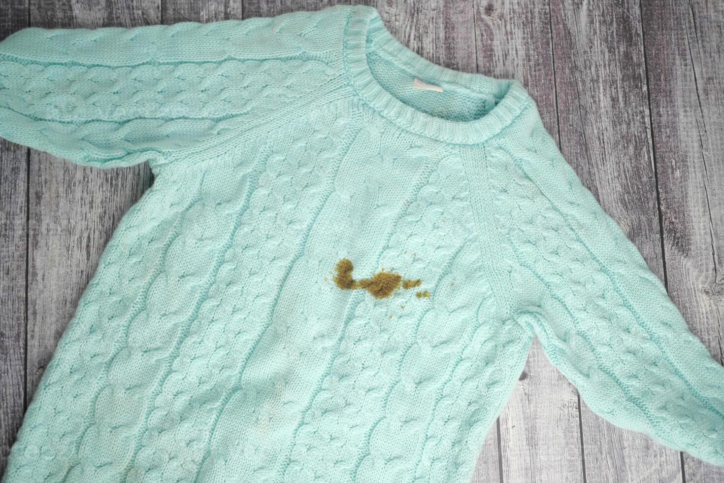 Sweater with a stain on a rustic wooden surface photo