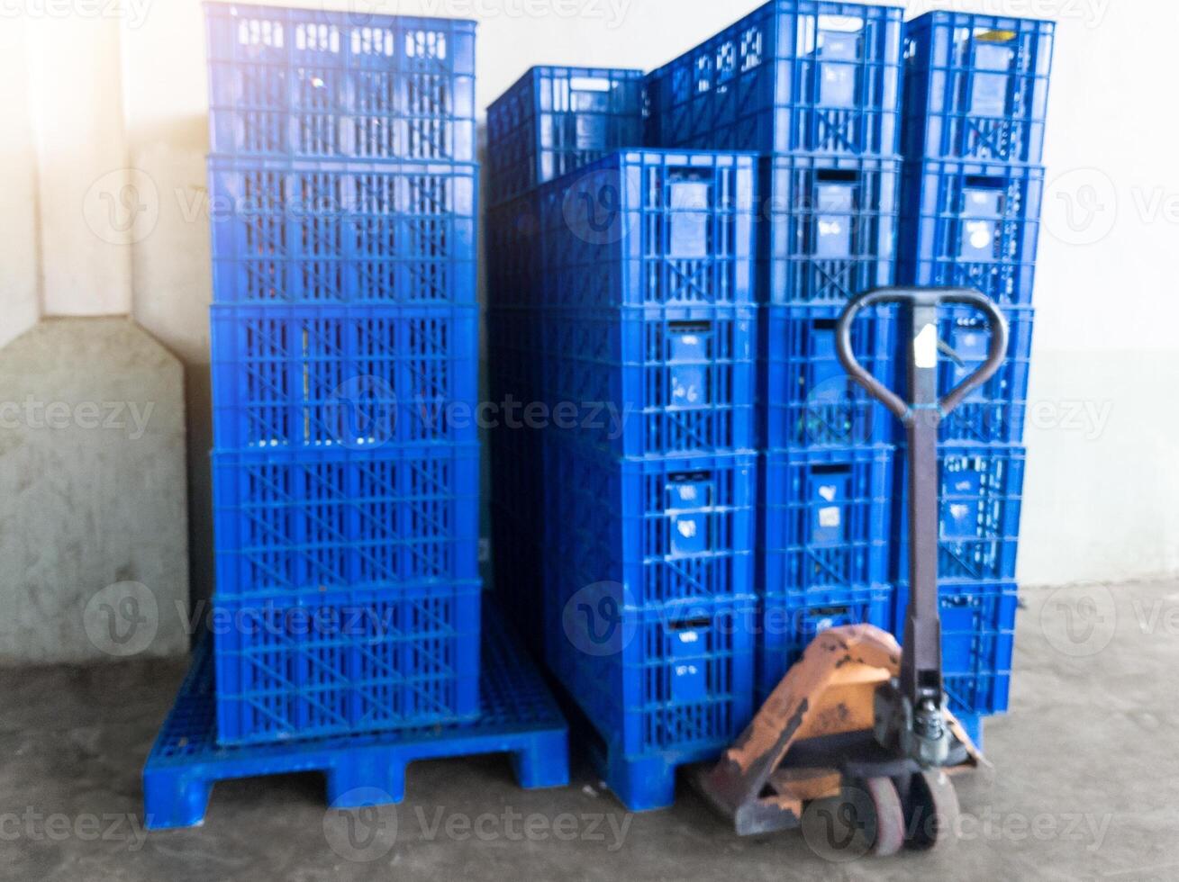 storage area with several stack of blue plastic crates ready for moving with hand pallet jack photo