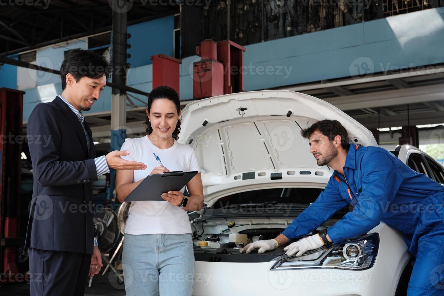 Warranty service work, Latin female client cheerful sign contract document from Asian male insurance agent, accept claim car fix from accident, mechanic behind at maintain automotive garage. photo