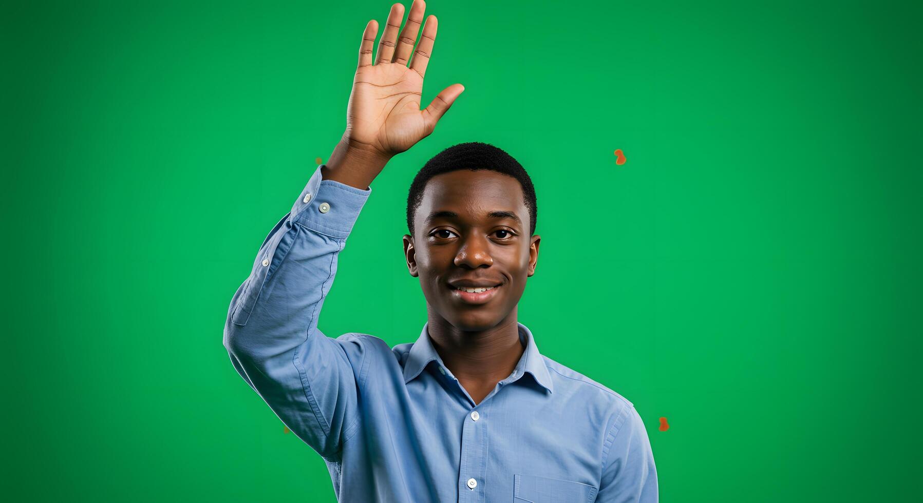A young man waving his hand in front of a green screen photo