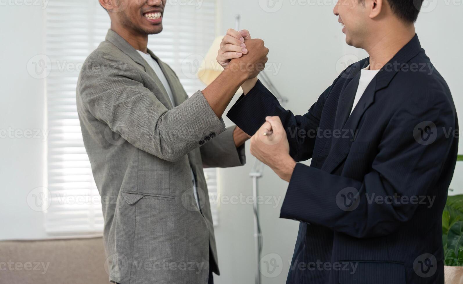 Playful Interaction and Team Spirit. Two men engaging in a friendly arm wrestling match in a bright office. photo