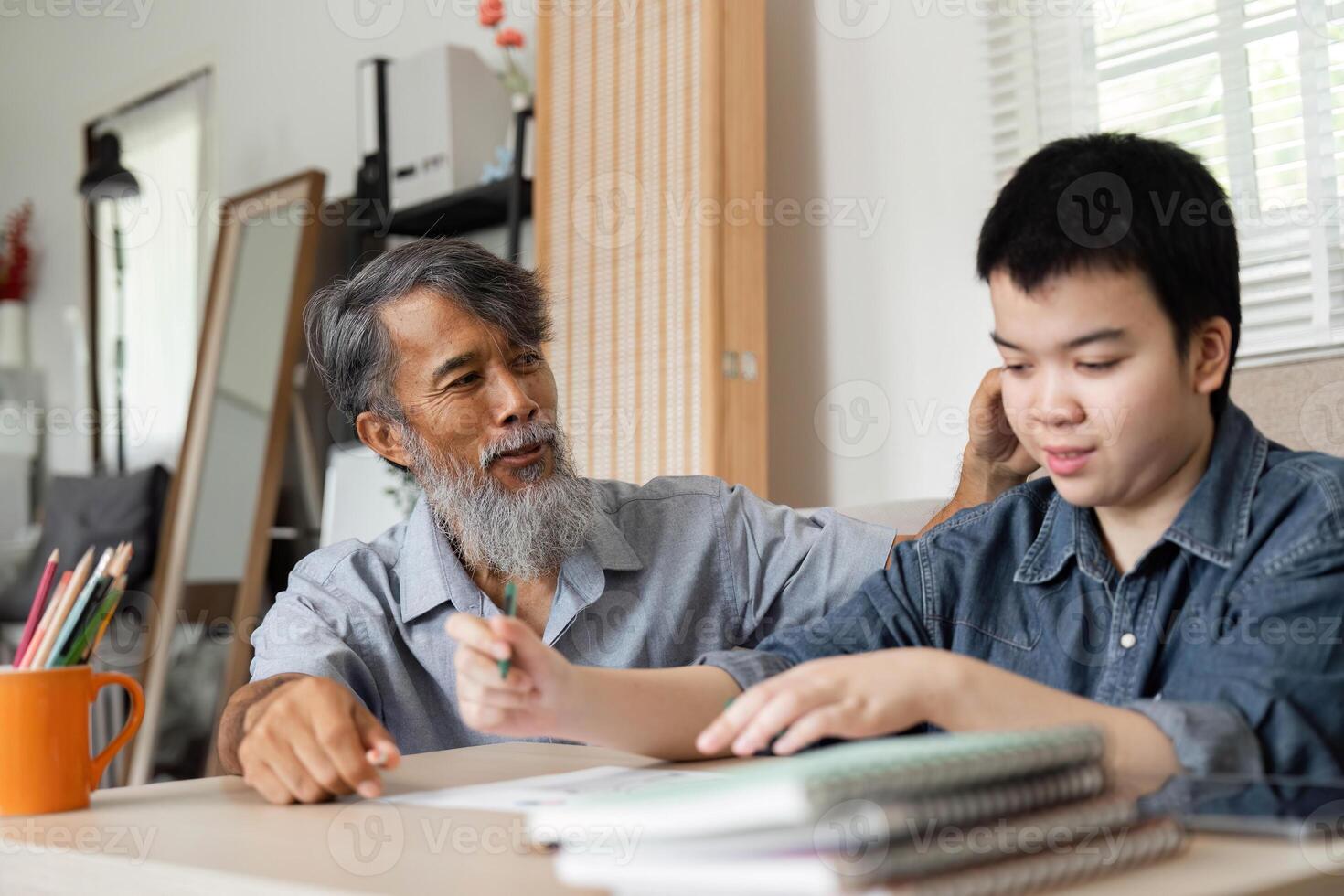 Artistic Expression and Family Support. A grandfather guides his grandson in creating drawings, fostering creativity and connection. photo