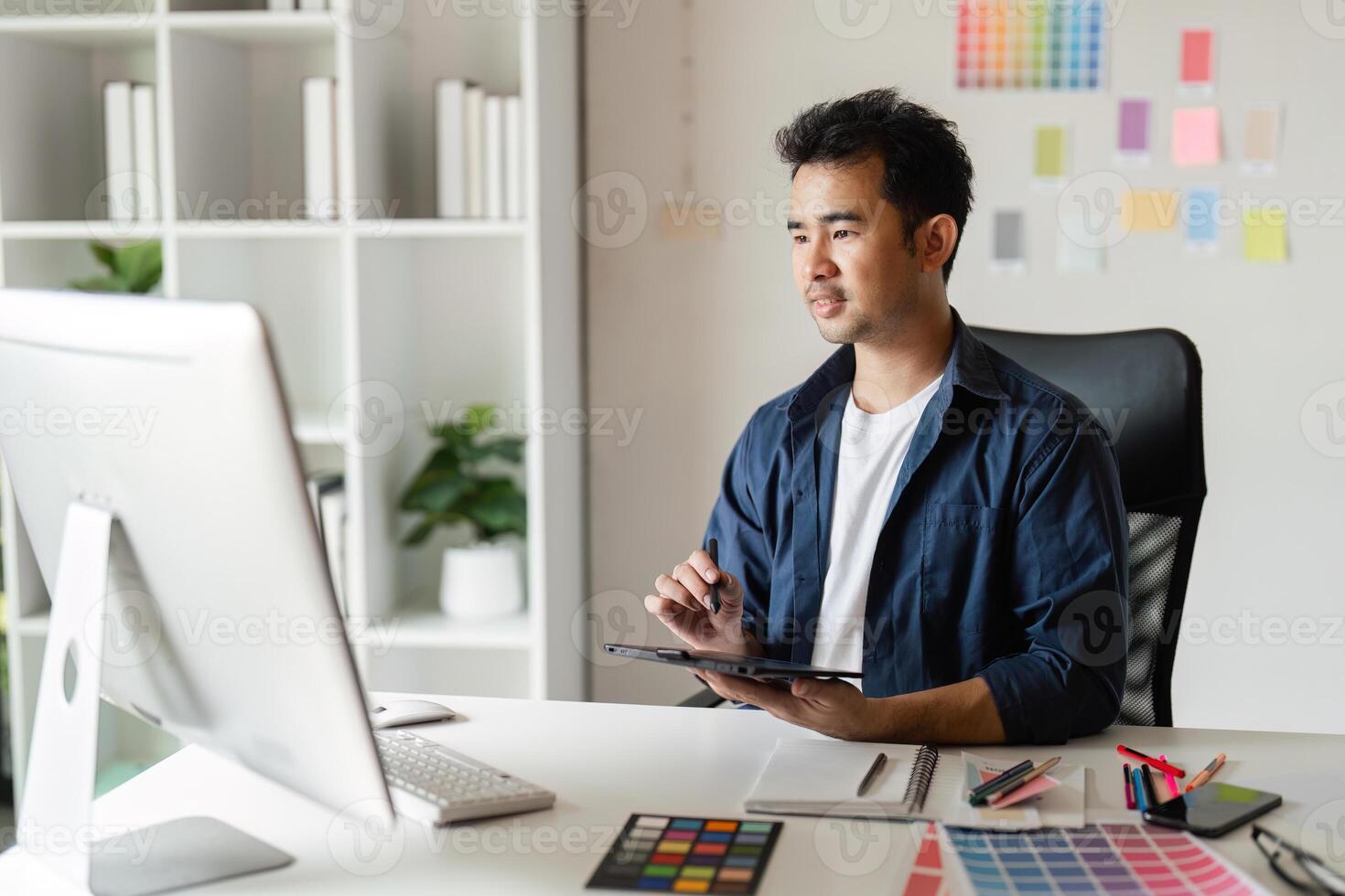 Creative Graphic Designer Working in Modern Design Studio with Digital Tools and Color Swatches for Innovative Projects photo