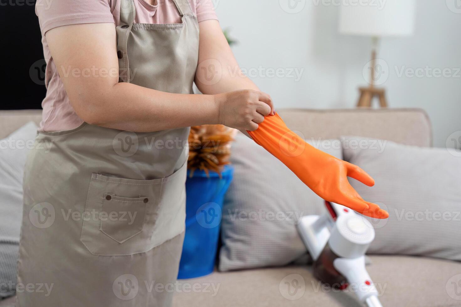Home Cleaning Preparation. A woman puts on orange gloves, ready for her cleaning tasks. photo