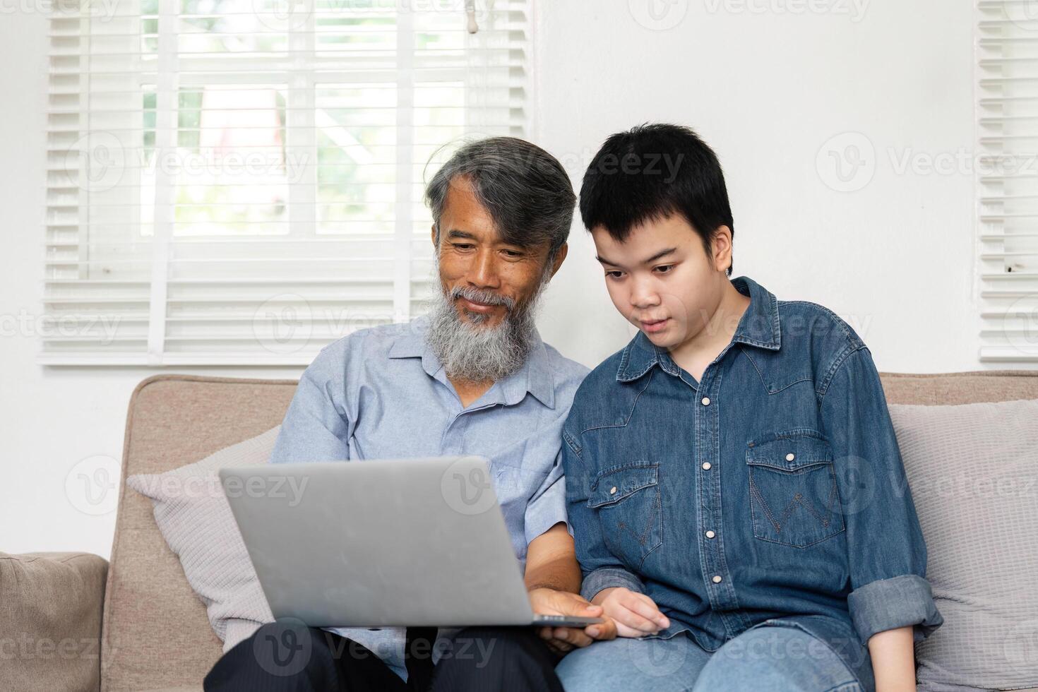 Collaboration and Learning. A grandfather and grandchild working together on a laptop at home. photo