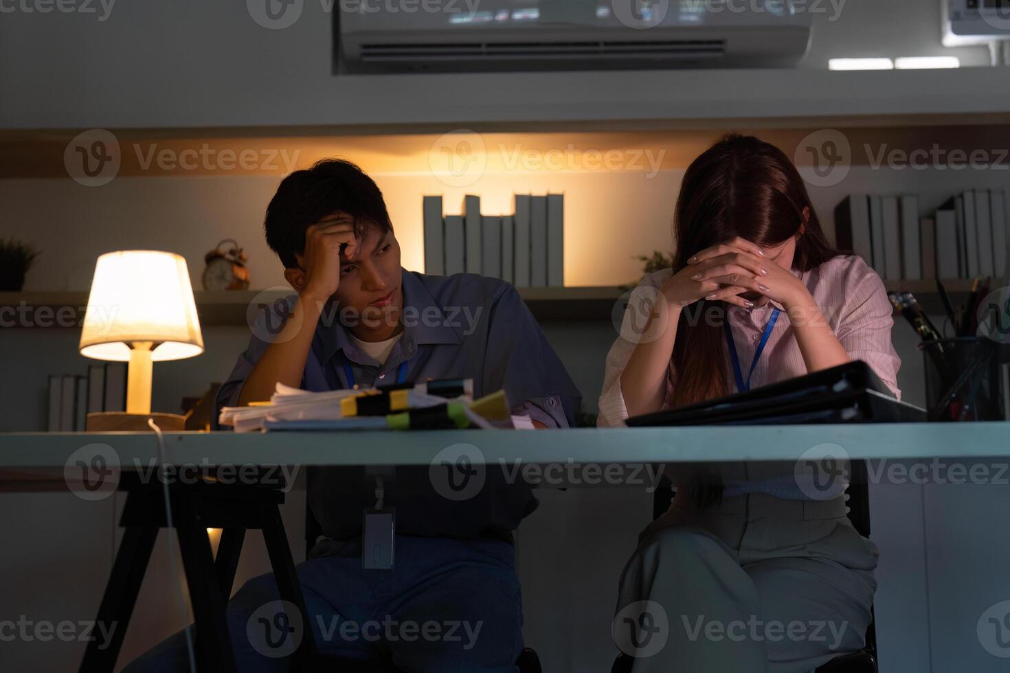 Stressed colleagues facing challenges in a dimly lit office photo