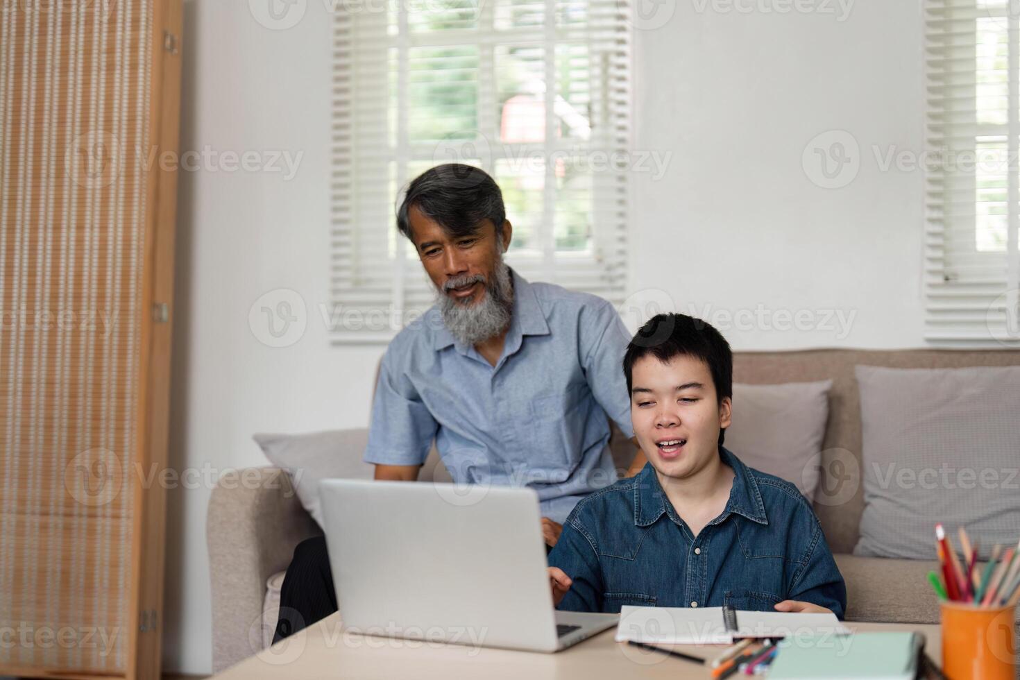 Joyful Moments in Family Life. A grandfather and grandson share an engaging online experience, highlighting the joy of family connections. photo