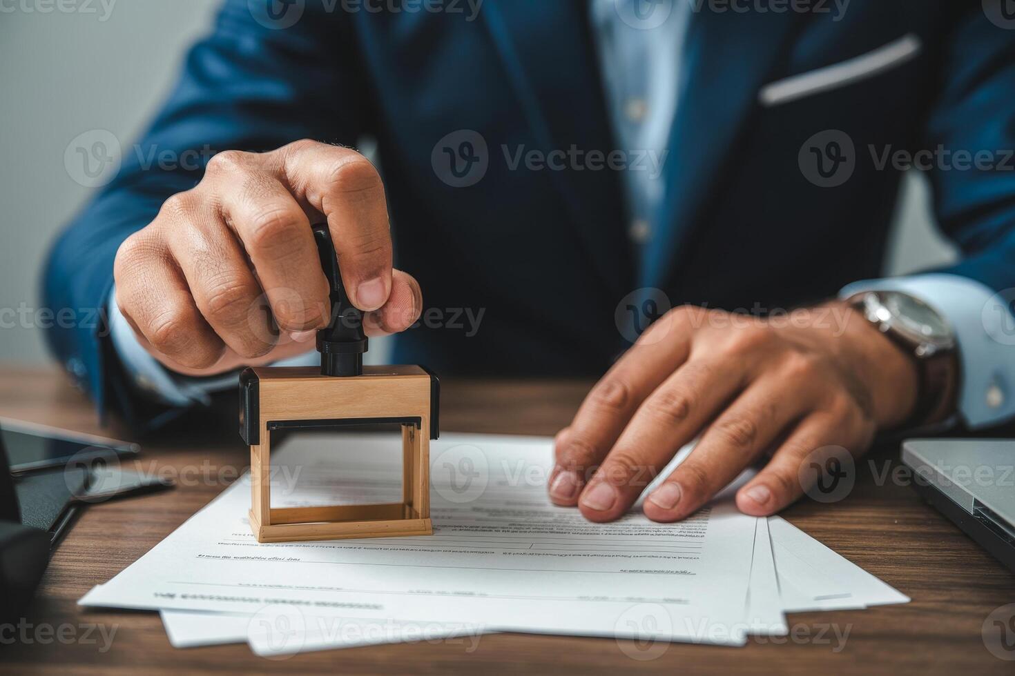 Business professional applying an official stamp to important documents in a modern office setting during the afternoon photo