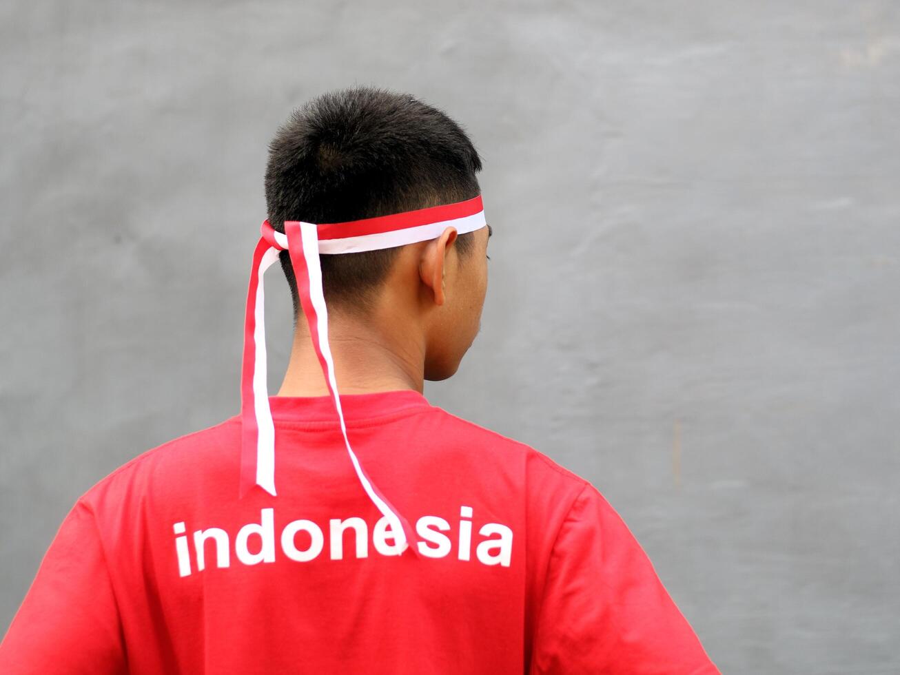 Indonesia teen wearing red white headband and clenched fist against grey background photo