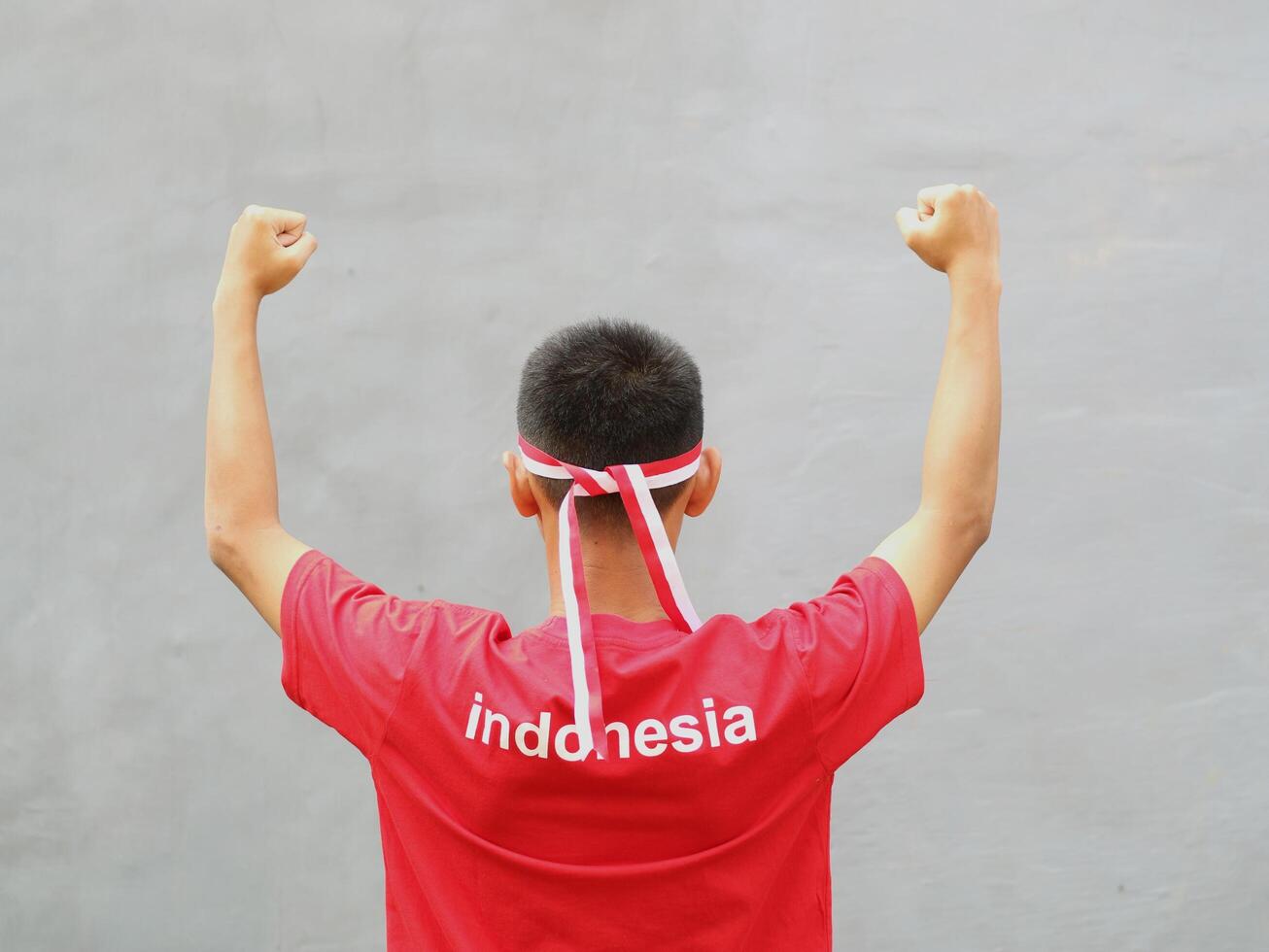 Indonesia young boy wearing red white headband and clenched fist against grey background photo
