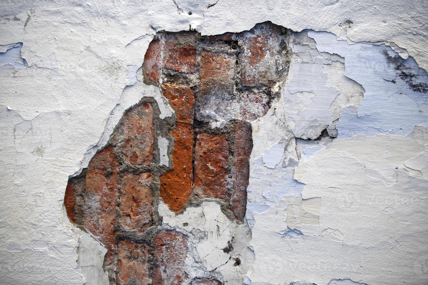 Aged Brick Wall Exposed Through Weathered Peeling Paint in Urban Setting photo