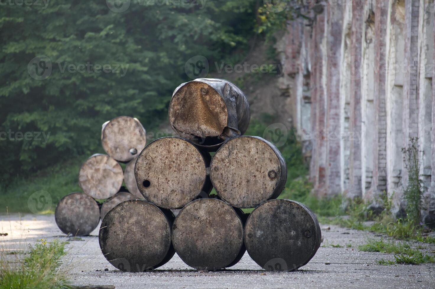 Stack of Weathered Metal Barrels Outdoors Near an Abandoned Wall in a Forest photo