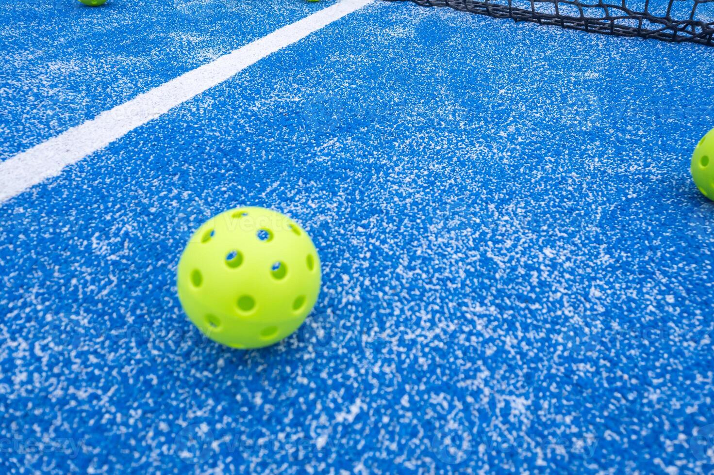 pickleball ball close to the net and the line of a blue pickleball court photo