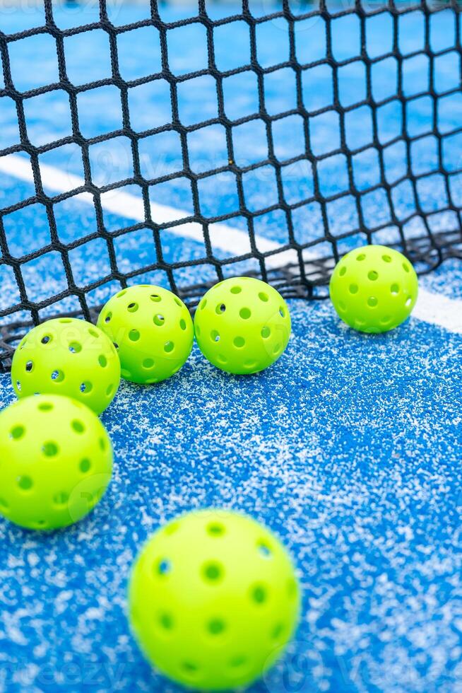 banner of a pickleball balls close to the net and the line of a blue pickleball court photo