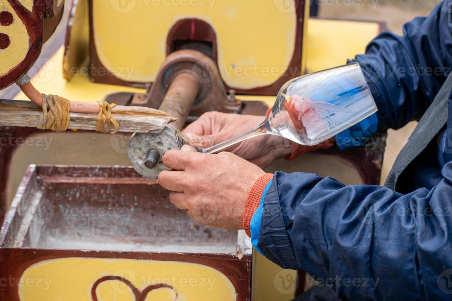 The hands of a craftsman using a grinding machine to polish glass. photo