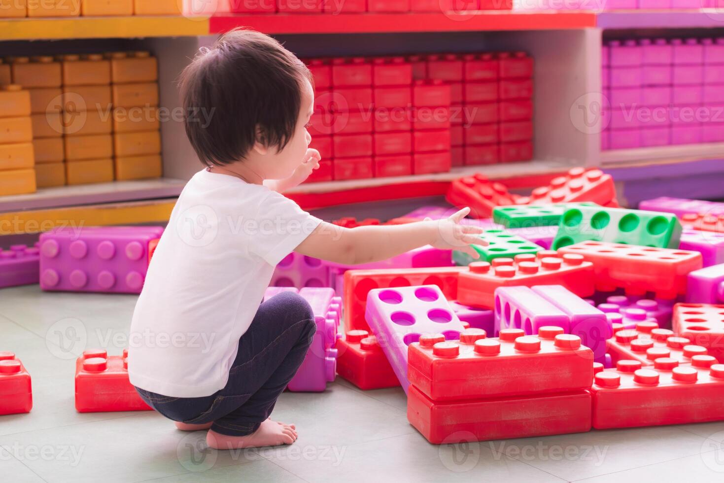 Little boy having fun stacking toy blocks on the floor. Activities to develop thinking skills and hand muscles. 2-year-old children. photo