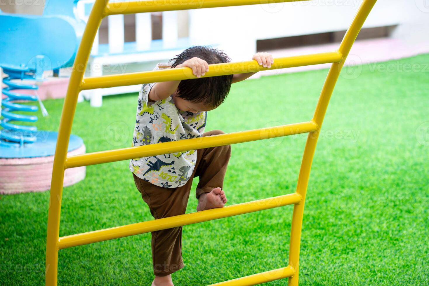 Cute little boy having fun on outdoor playground. Asian child climbing the stairs. Family time. Kid son aged 2 years old. photo