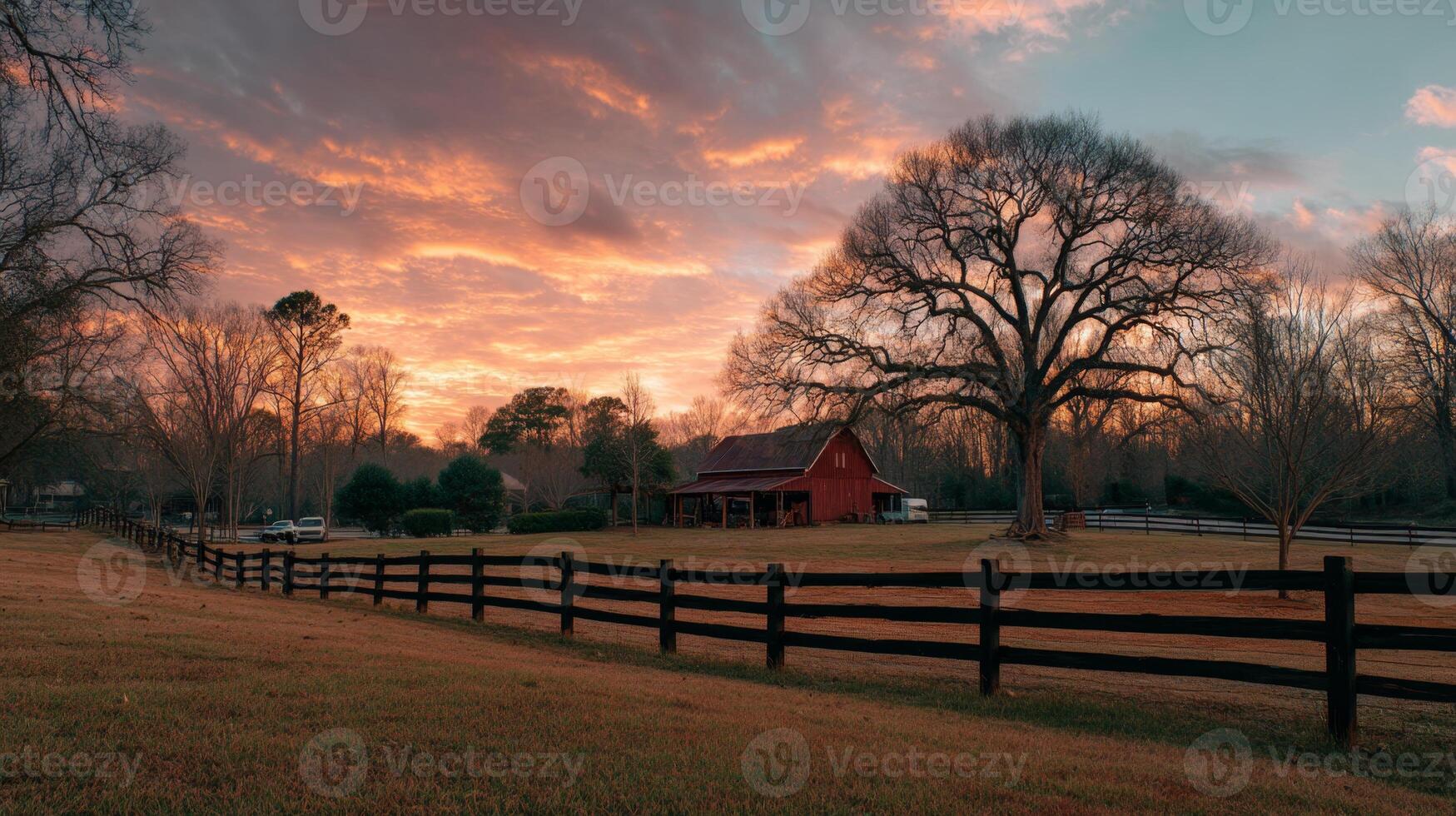 Serene Country Landscape with Rustic Barn, Majestic Tree, and Colorful Sunset Over Peaceful Rural Field photo