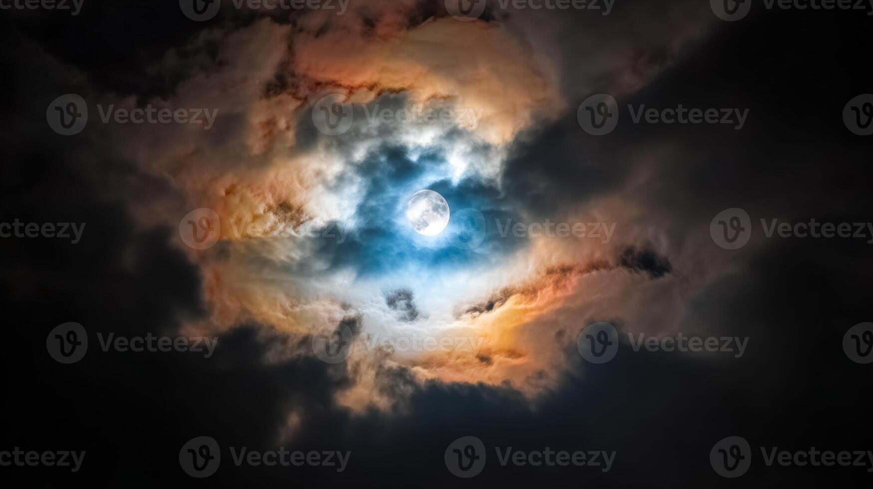 Mysterious Clouds Surrounding a Full Moon Illuminating the Night Sky with Colorful Rays of Light and Deep Shadows photo