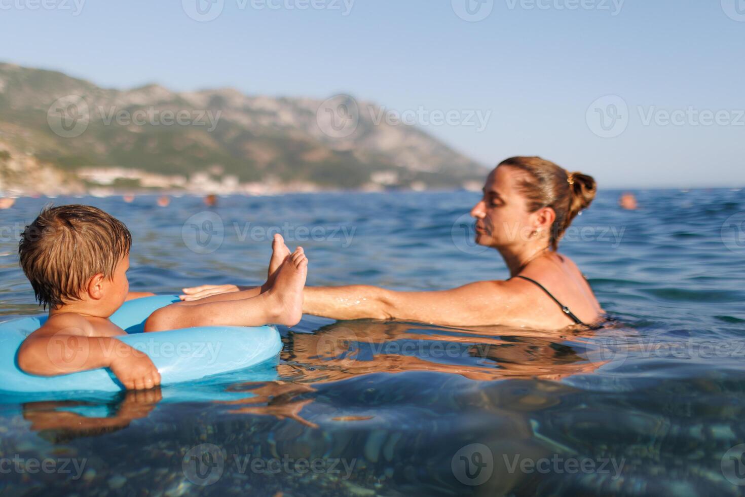 Caring mother rides her son on an inflatable ring in the seaCaring mother rides son inflatable ring seaMother rides son on inflatable ring in seaMother rides son on inflatable ring in sea photo