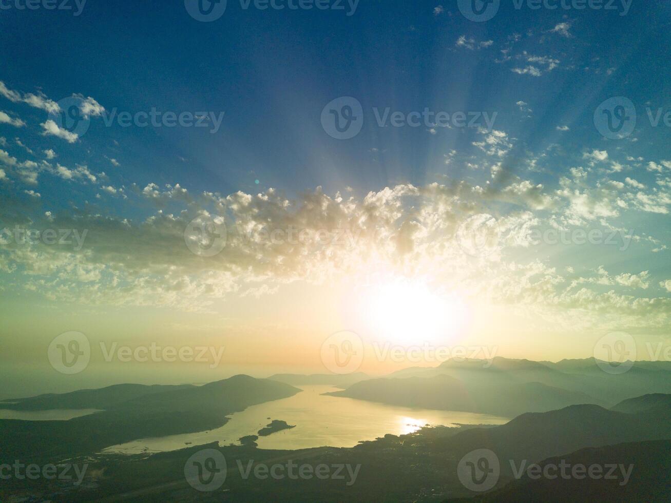 Dazzling sun in the evening sky illuminates all the peaks of the photo
