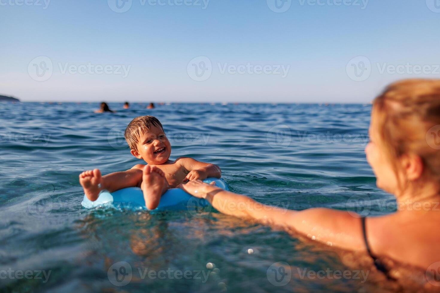 Caring mother rides her son on an inflatable ring in the seaMother rides son on inflatable ring in seaMother rides son on inflatable ring in sea photo