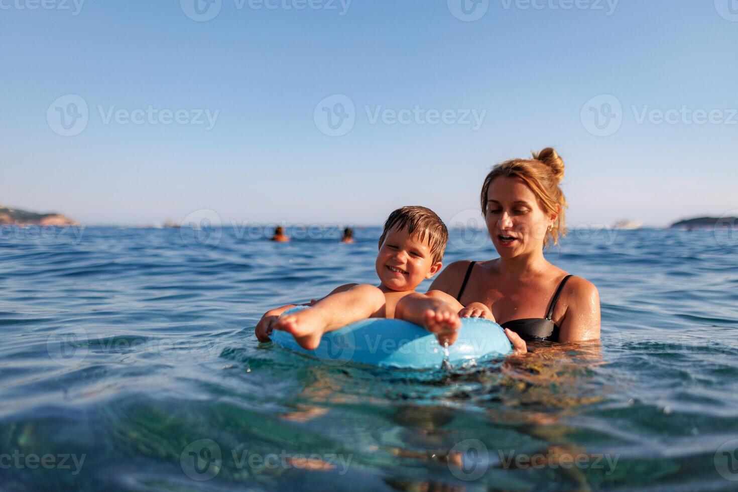 Caring mother rides her son on an inflatable ring in the seaMother floats son on inflatable ring in sea photo