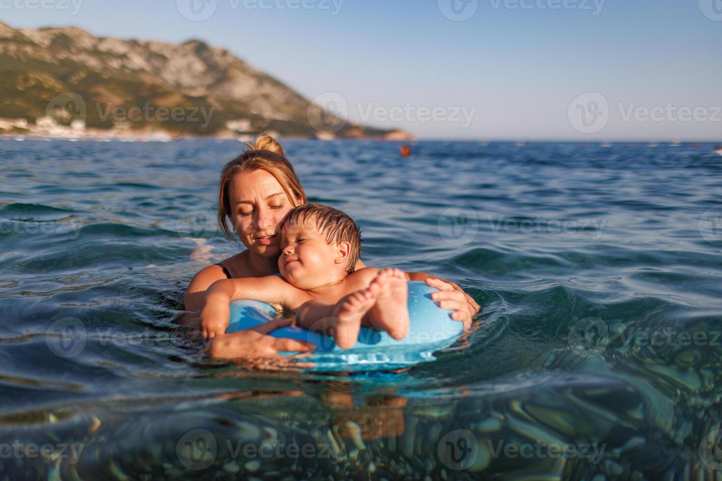 Caring mother rides her son on an inflatable ring in the seaMother rides son on inflatable ring in seaCaring mother rides son on inflatable ring photo