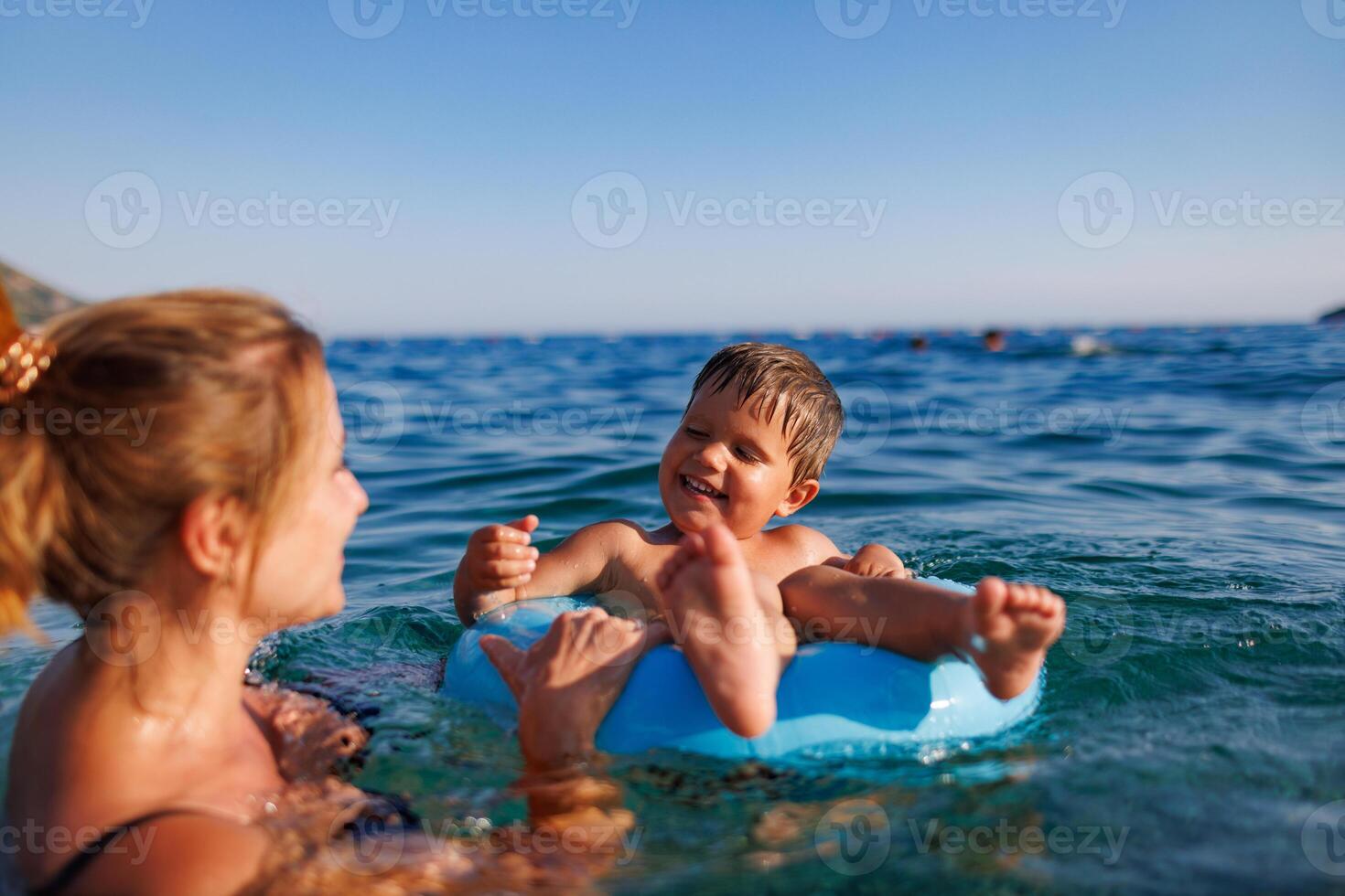 Caring mother rides her son on an inflatable ring in the seaMother rides son on inflatable ring in seaMother rides son on inflatable ring in seaMother rides son inflatable ring sea photo