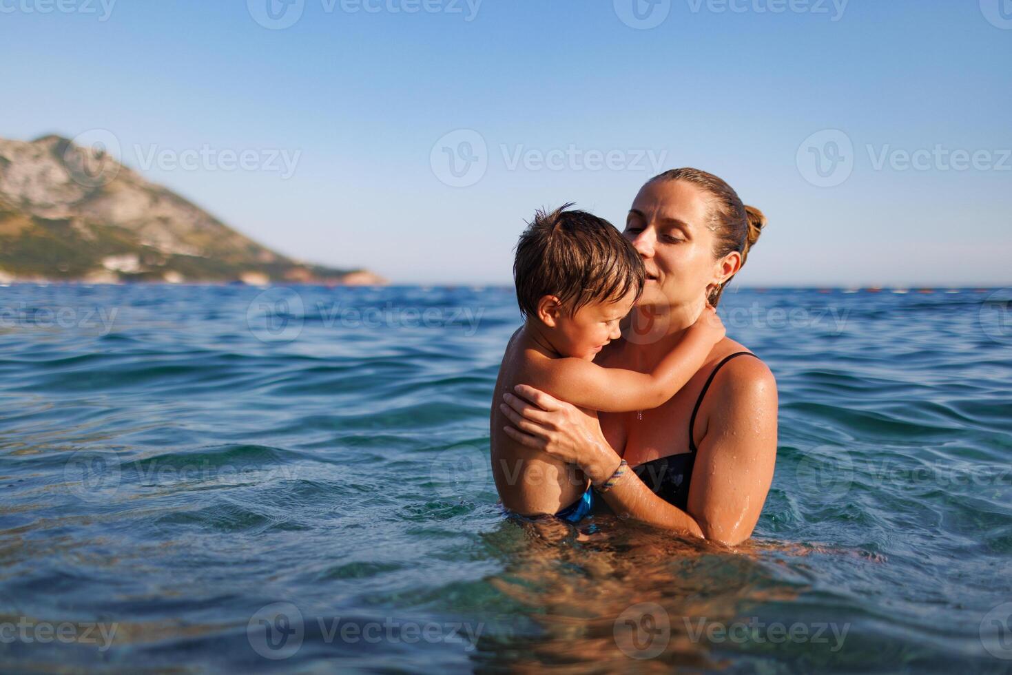 Cheerful mother plays with her son in the seaMother plays happily with son in sea photo
