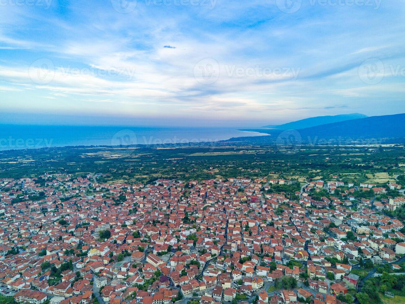 Greek town of Litochoro with small houses and green vegetation against the backdrop of the Aegean Sea and a cloudy sky photo