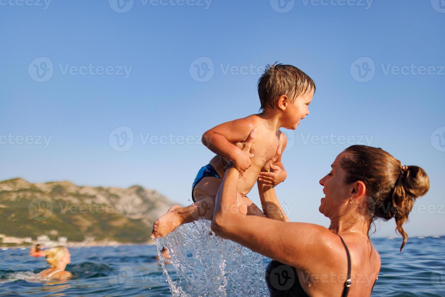 Cheerful mother plays with her son in the seaCheerful mother plays with son seaCheerful mother plays with son at sea photo