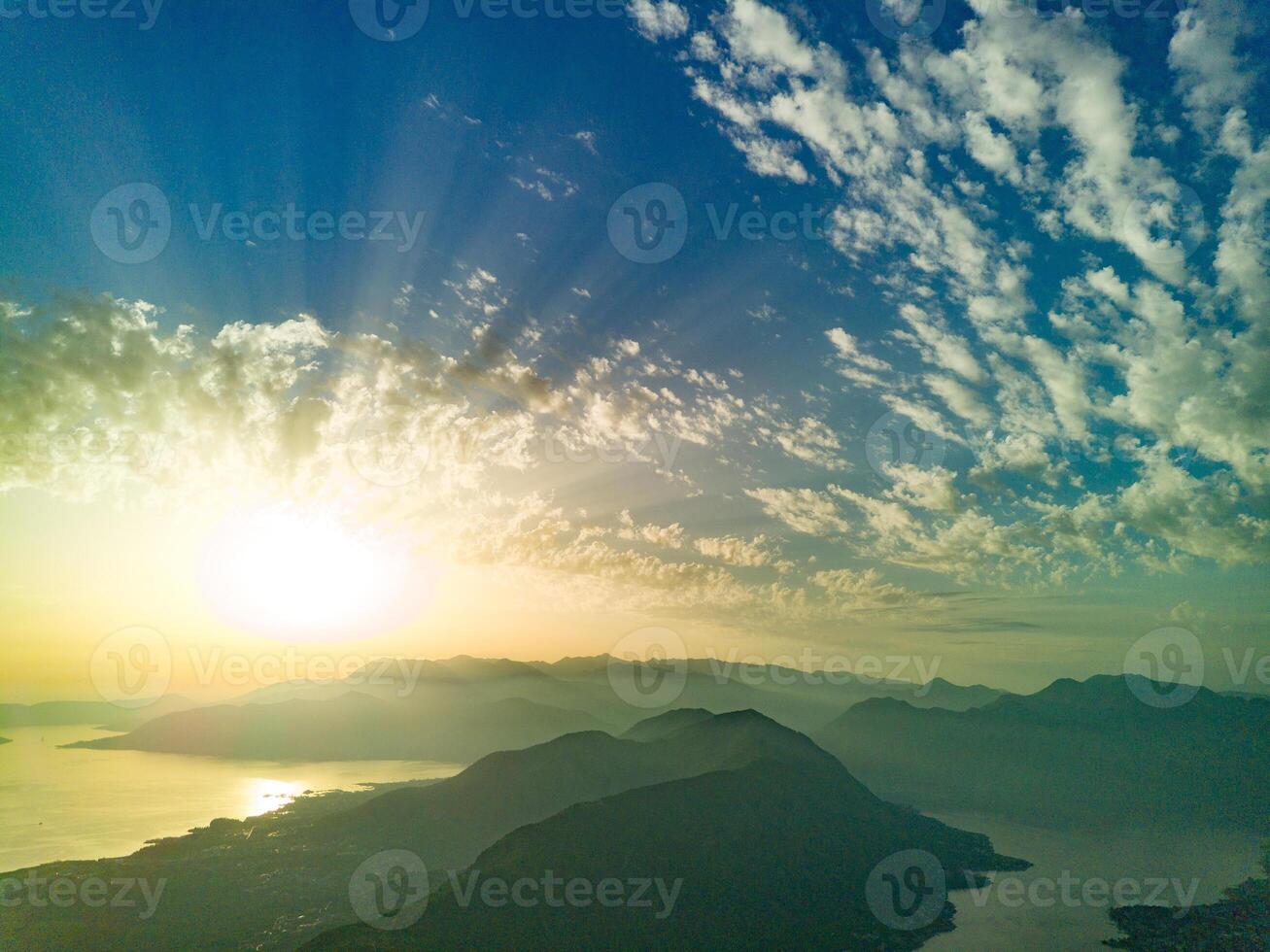 Dazzling sun in the evening sky illuminates all the peaks of the Balkan Montenegrin mountains and the coast of Kotor Bay photo
