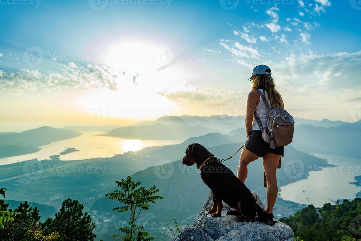 Hiker with dog overlooking mountain sunset photo