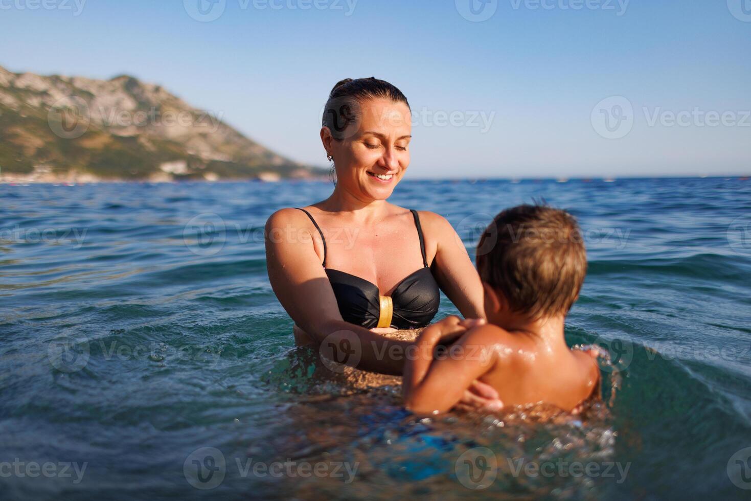 Cheerful mother plays with her son in the seaMother plays happily with son in seaMother plays happily with son in sea photo