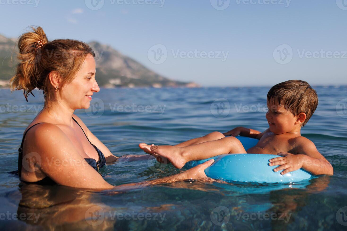 Caring mother rides her son on an inflatable ring in the seaCaring mother rides son inflatable ring seaMother rides son on inflatable ring in seaMother rides son on inflatable ring sea photo