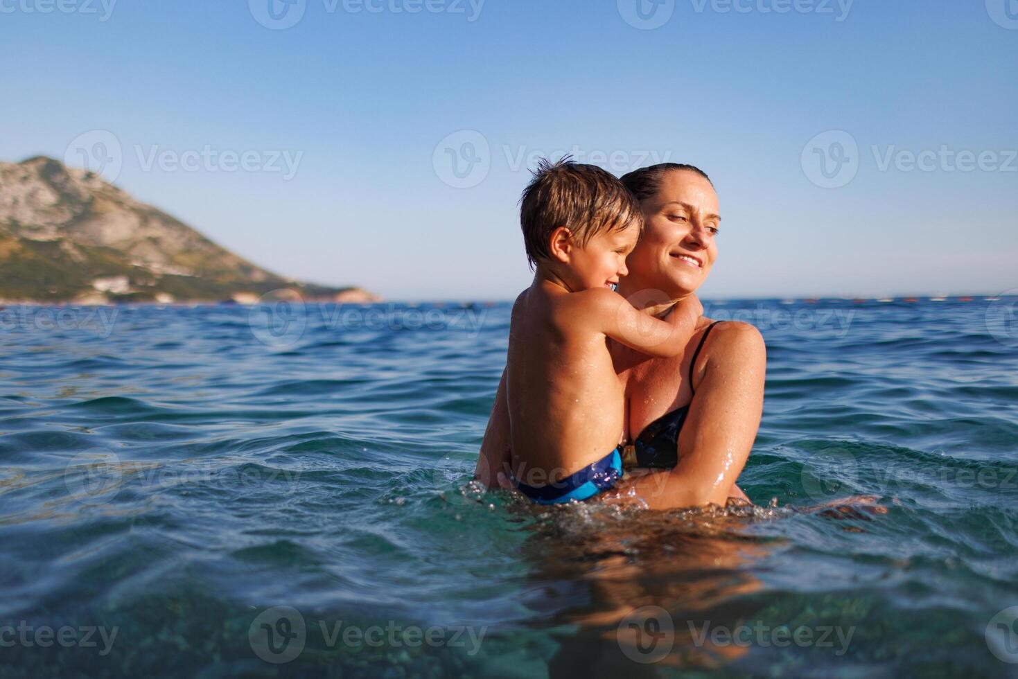 Cheerful mother plays with her son in the seaPlayful mother and son at sea photo