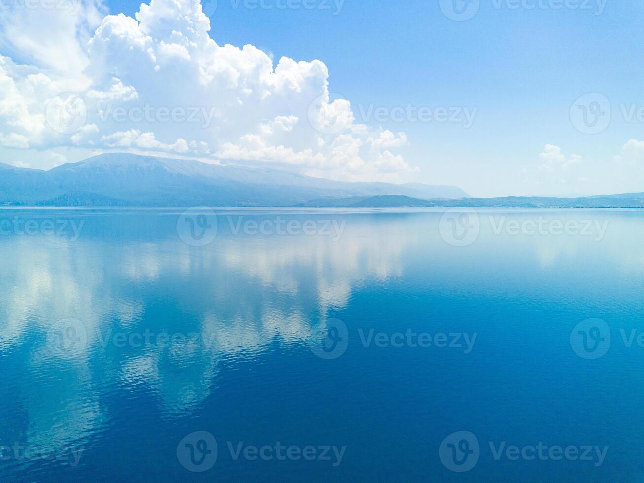 Clouds float across the daytime sky above the horizon with the Adriatic Sea in the light of the sun photo
