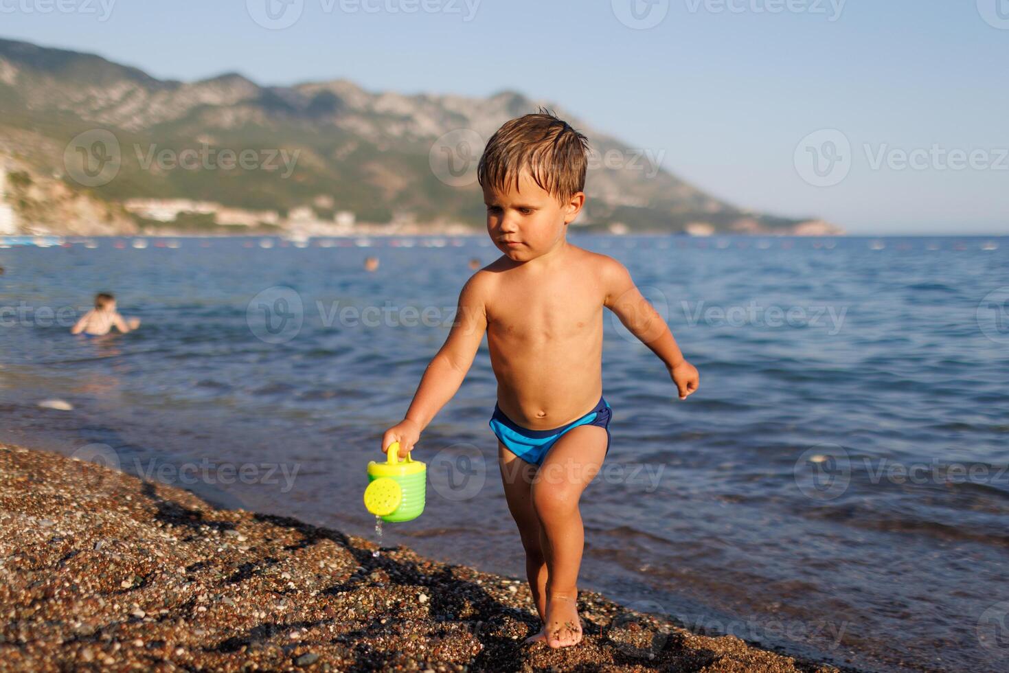 Little boy runs along the sandy shore with a toy sprinklerLittle boy runs along sandy shore with toy sprinkler photo