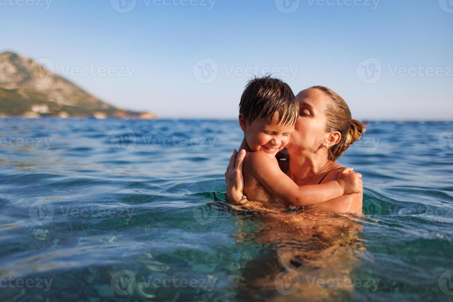 Cheerful mother plays with her son in the seaHappy mother plays with son at sea photo